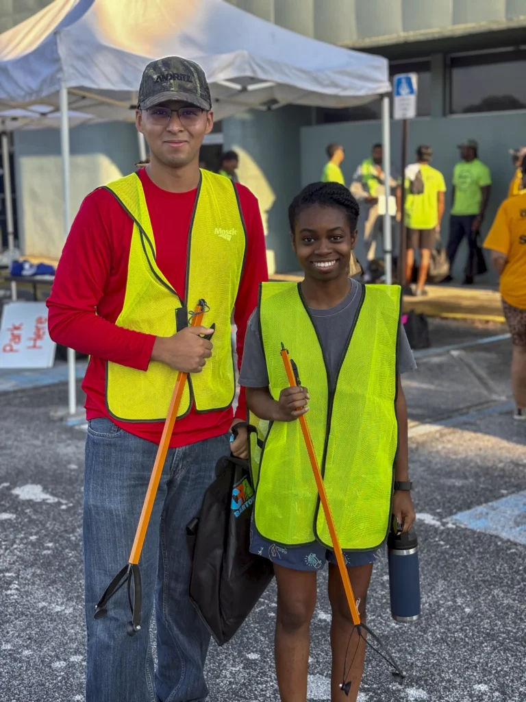 Two volunteers wearing safety vests and holding litter grabbers at a Bartow CRA community cleanup event