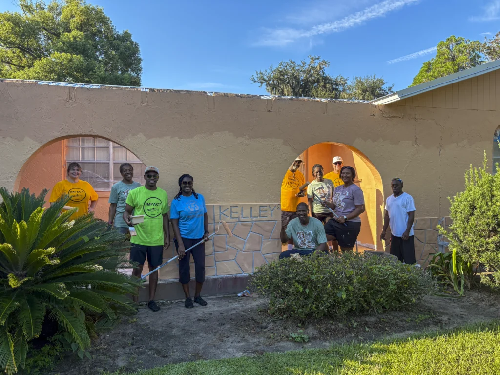 Volunteers gathered in front of a freshly painted orange building with arched windows during a Bartow CRA community improvement project