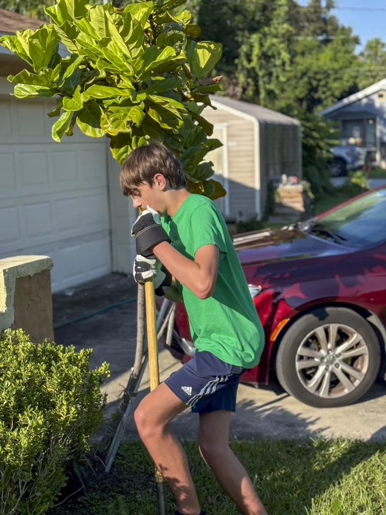Young volunteer using a hoe to work in a yard during a Bartow CRA neighborhood cleanup