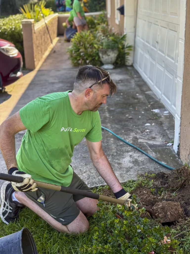 Publix Serves volunteer kneeling and digging in a garden bed during a Bartow neighborhood cleanup