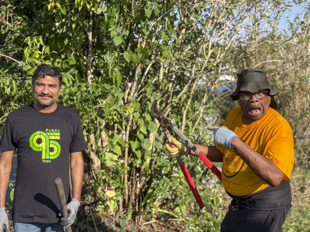 Two volunteers trimming overgrown vegetation during a Bartow CRA community cleanup event