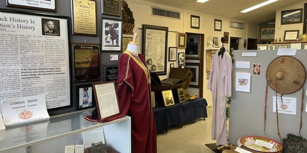 Interior of the African American Heritage Museum in Bartow with framed historical displays and a graduation robe on a mannequin