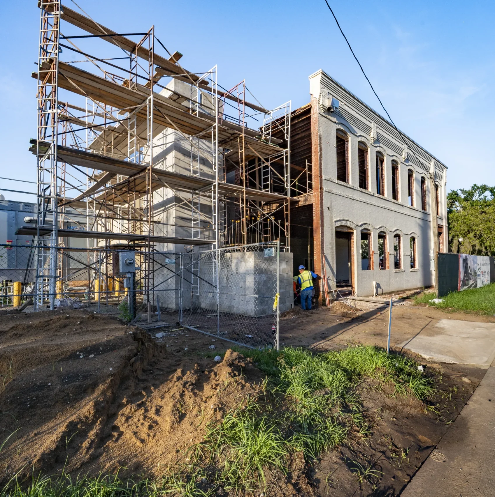 Historic downtown Bartow building under restoration scaffolding with a worker on site near the brick facade